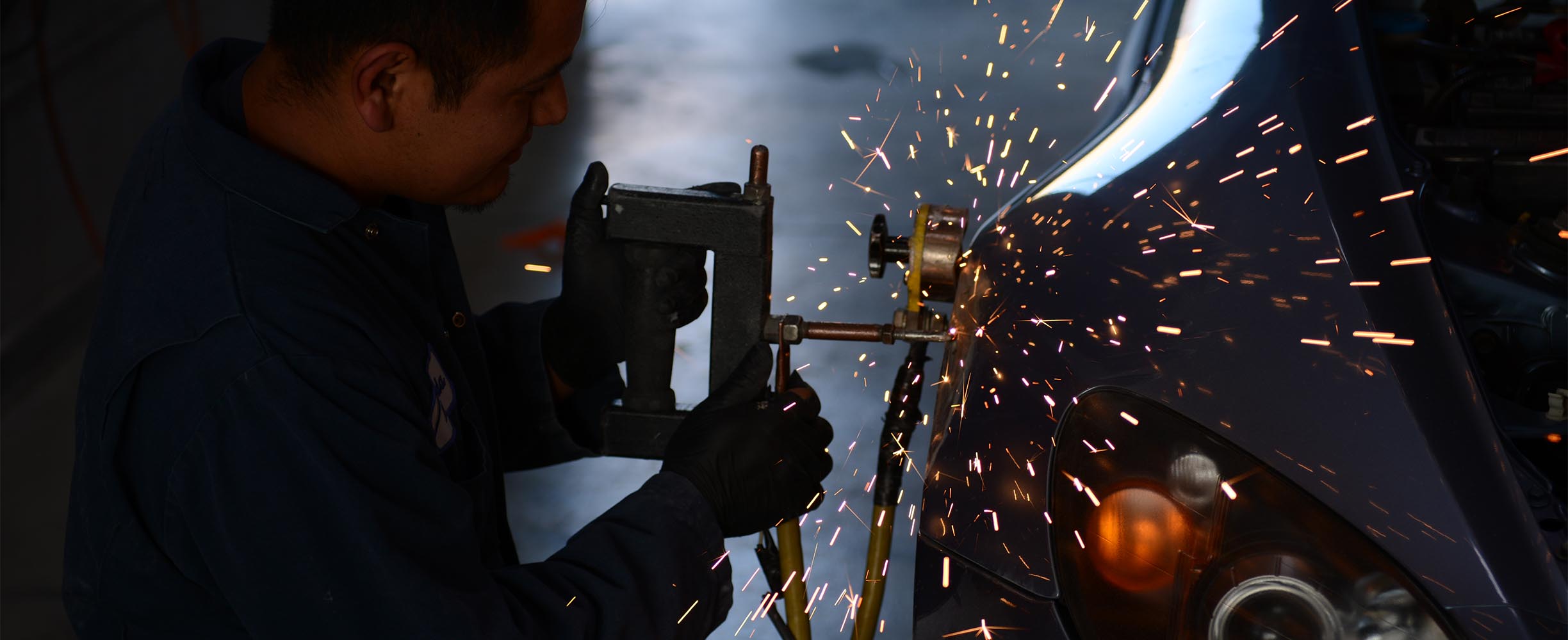 Technician repairing collision damage on a vehicle body panel